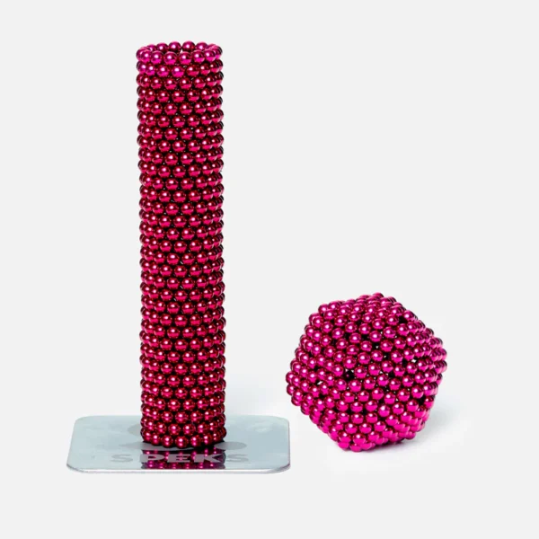 Bunte magnetische Kugeln in Pink, geformt zu einer Turm- und einer Ballskulptur, die auf einer weißen Oberfläche stehen.
