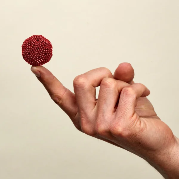 Glitzernder roter Ball auf dem Zeigefinger einer Hand.