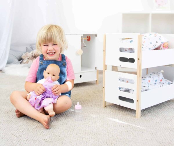 Der Small Foot Puppenschrank aus der Reihe „Little Button“ bietet mit einer Höhe von 48 cm viel Platz für Puppenkleider aller Art. Mit den leicht gängigen Flügeltüren kannst du den Puppenschrank bequem öffnen. Im Inneren findest du deine Kleiderstange und ein Fach, um Sachen zu verstauen. Ebenfalls enthalten sind spezielle Kleiderbügel, die über ein Gummiband verfügen. Damit eignen sie sich auch gut, um kleine Teile wie Schuhe oder Tücher zu verstauen. Um sicheres Spielen zu gewährleisten, sind alle Kanten abgerundet. Die weiße Farbgebung des Puppenschranks weiß sowohl Mädchen als auch Jungen zu gefallen. Der Schrank ist für Kinder ab 3 Jahren geeignet und passt perfekt zu allen anderen Produkten der „Little Button“-Reihe.