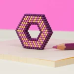 Bilderdatei, Alt-Text: Bärentatze aus bunten Perlen in Lila, Pink, und Gelb, auf hellem Hintergrund.