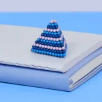 2. Blaublaue Kugel-Pyramide auf einem weißen Buch mit blauer Ledereinband, moderne Deko-Elemente.