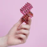 Akkordeon aus kleinen, bunten Hochleistungsbatterien gegen Pinkhintergrund.