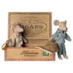 Handgefertigte Stofftier-Mäuse in Vintage-Design, eines trägt Polka-Dot-Kleid mit Tasche, das andere trägt Pyjamas, vor einer Zigarre-Box aus Holz, ideal für nostalgische Dekorationen oder als Sammlerstücke.