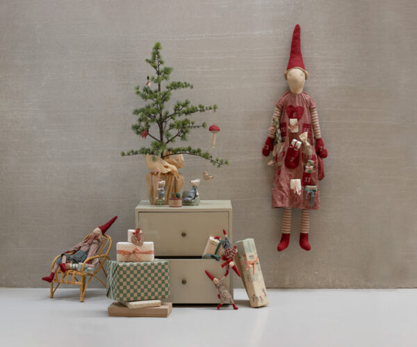 4. Eine festliche Weihnachtsdekoration mit kleinen Geschenkboxen, einem Mini-Weihnachtsbaum, Kuschel-Figuren und einem adventlichen Adventskalender-Wichtel. Das Arrangement ist liebevoll gestaltet und strahlt eine warme, gemütliche Atmosphäre aus.