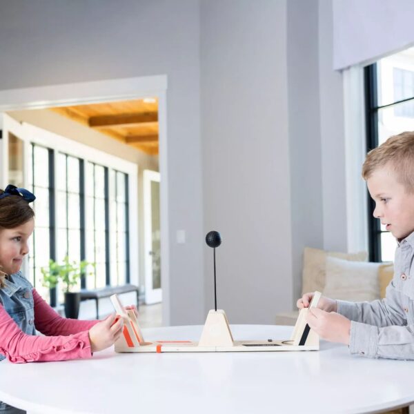 Kinder spielen an einem Tisch mit einem Backgammon-Spiel.
